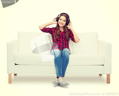 Image of teenage girl sitting on sofa with headphones