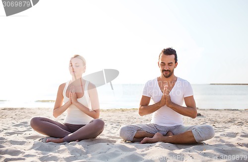 Image of smiling couple making yoga exercises outdoors