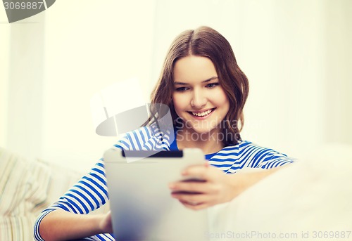 Image of smiling teenage girl with tablet pc at home