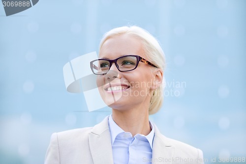 Image of young smiling businesswoman over office building