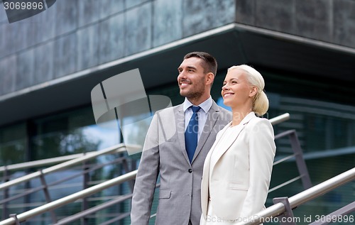 Image of smiling businessmen standing over office building