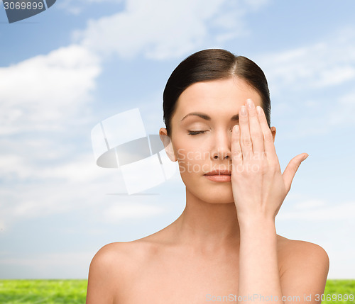 Image of smiling young woman covering face with hand