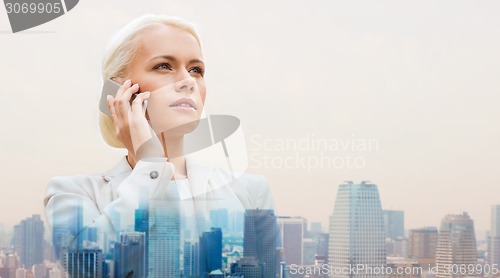 Image of serious businesswoman with smartphone in city