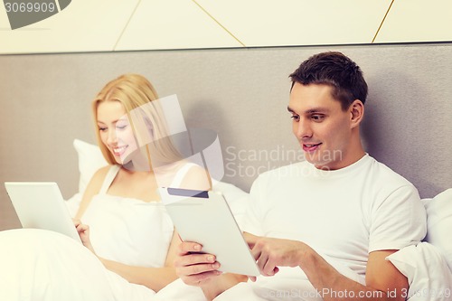 Image of smiling couple in bed with tablet pc computers