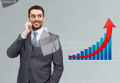 Image of young smiling businessman calling on smartphone