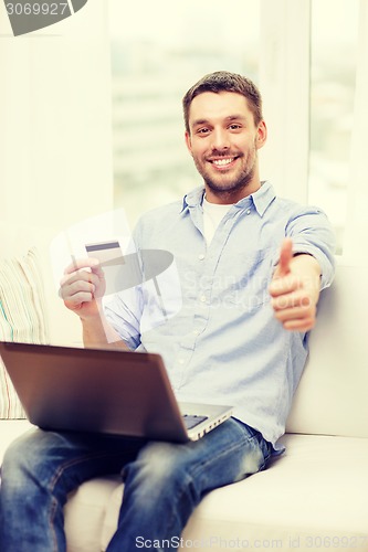 Image of smiling man working with laptop and credit card