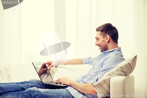 Image of smiling man working with laptop at home