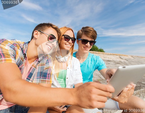 Image of group of smiling friends with tablet pc outdoors