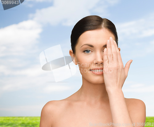 Image of smiling young woman covering face with hand