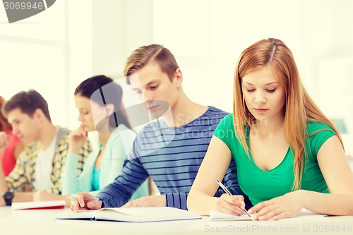 Image of tired students with textbooks and books at school