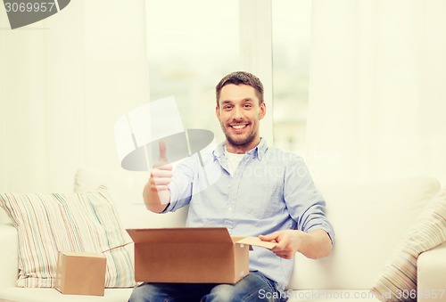 Image of man with cardboard boxes at home showing thumbs up