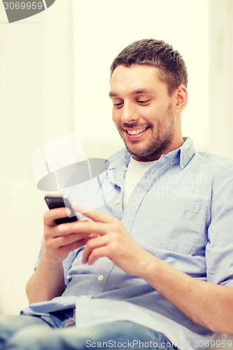 Image of smiling man with smartphone at home