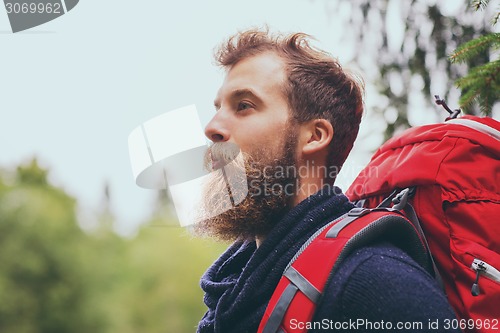 Image of smiling man with beard and backpack hiking