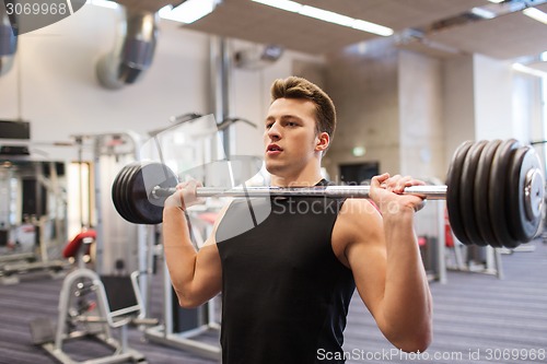 Image of young man flexing muscles with barbell in gym