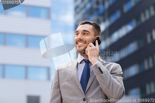 Image of smiling businessman with smartphone outdoors