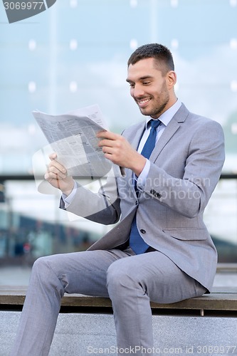 Image of young smiling businessman newspaper outdoors