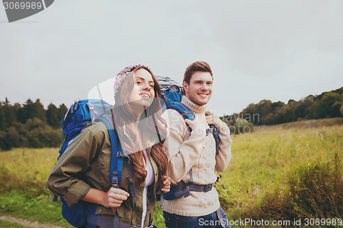 Image of smiling couple with backpacks hiking