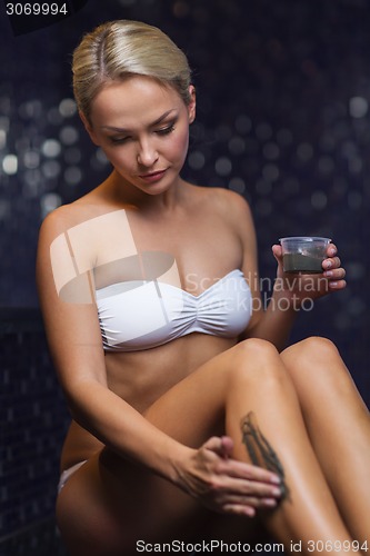 Image of beautiful woman applying therapeutic mud in spa