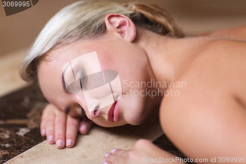 Image of young woman lying on hammam table in turkish bath