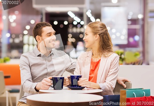 Image of happy couple with shopping bags drinking coffee