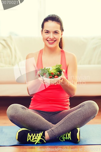 Image of smiling teenage girl with green salad at home
