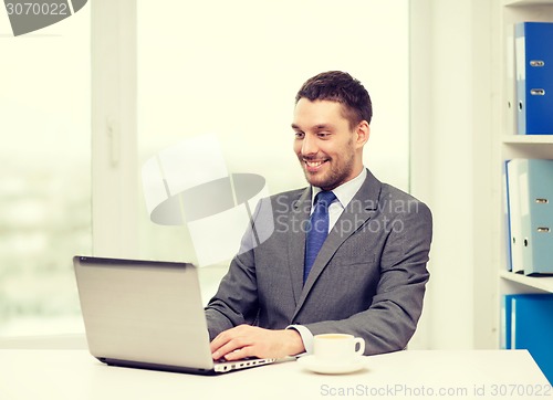Image of smiling businessman with laptop and coffee