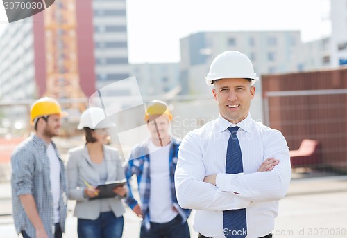 Image of group of smiling builders in hardhats outdoors