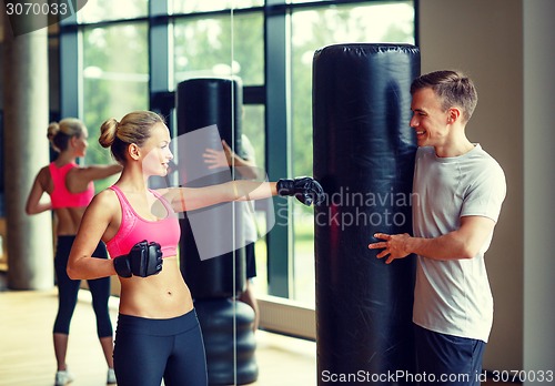 Image of smiling woman with personal trainer boxing in gym