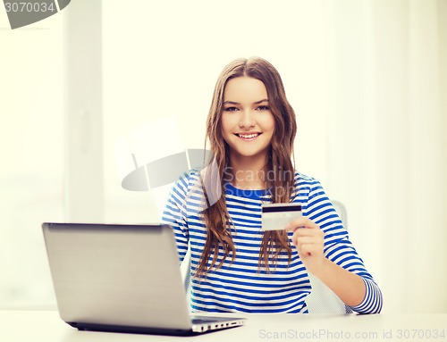 Image of smiling teenage gitl with laptop computer at home