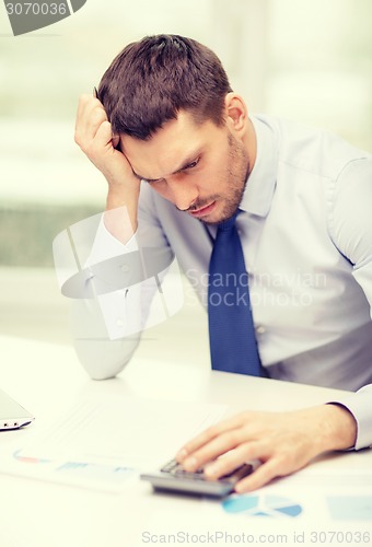 Image of stressed businessman with laptop and documents