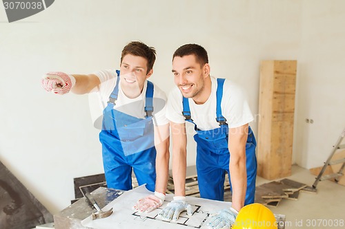 Image of smiling builders with blueprint