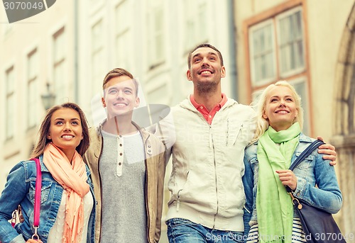 Image of group of smiling friends walking in the city