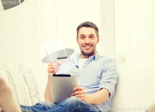 Image of smiling man working with tablet pc at home