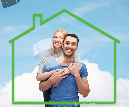 Image of smiling couple hugging over green house