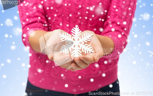 Image of close up of woman in sweater holding snowflake