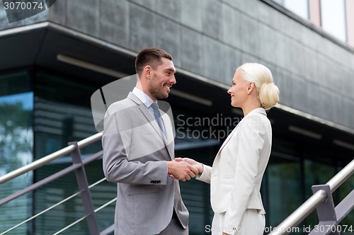 Image of smiling businessmen shaking hands on street