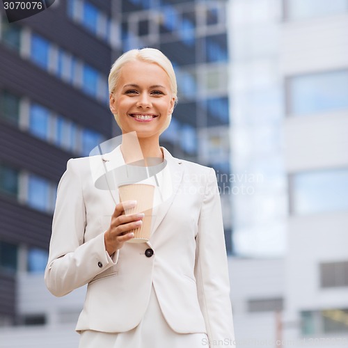 Image of smiling businesswoman with paper cup outdoors