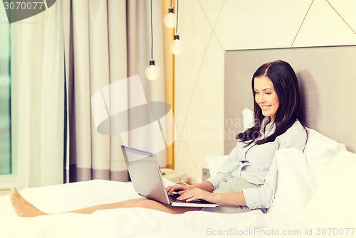 Image of happy businesswoman with laptop in hotel room