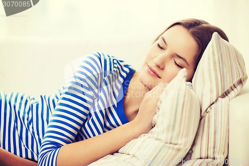 Image of smiling teenage girl sleeping on sofa at home