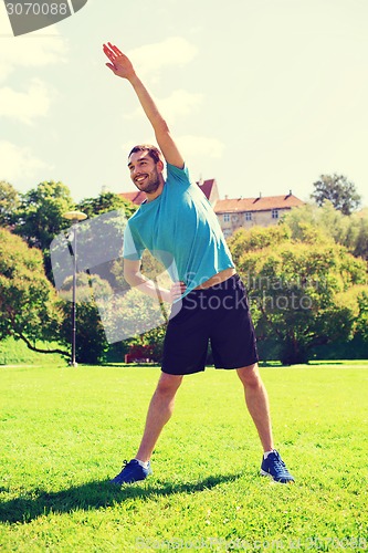 Image of smiling man stretching outdoors