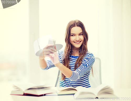 Image of smiling student girl with smartphone and books