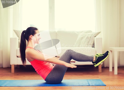 Image of smiling girl doing exercise on floor at home