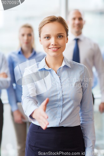 Image of smiling businesswoman making handshake in office