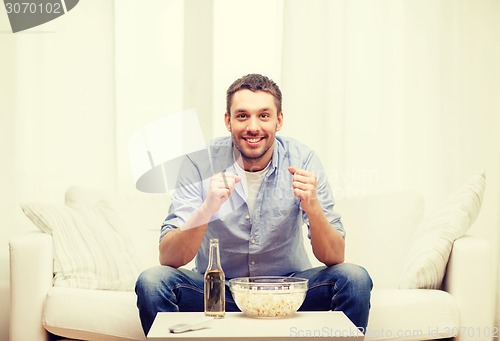 Image of smiling man watching sports at home