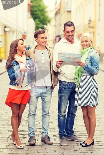 Image of group of smiling friends with map and photocamera