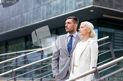 Image of serious businessmen standing over office building