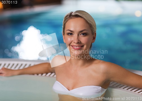 Image of happy woman sitting in jacuzzi at poolside