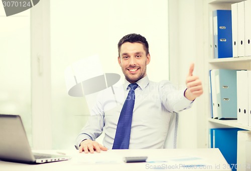 Image of smiling businessman with laptop and documents