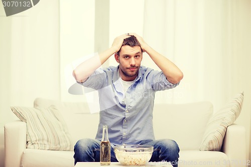 Image of sad man watching sports at home