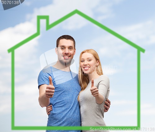 Image of smiling couple showing thumbs up over green house